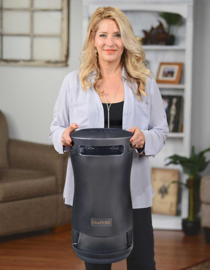 Woman holding black EdenPURE 360 Super Climater space heater and cooler with digital display indoors