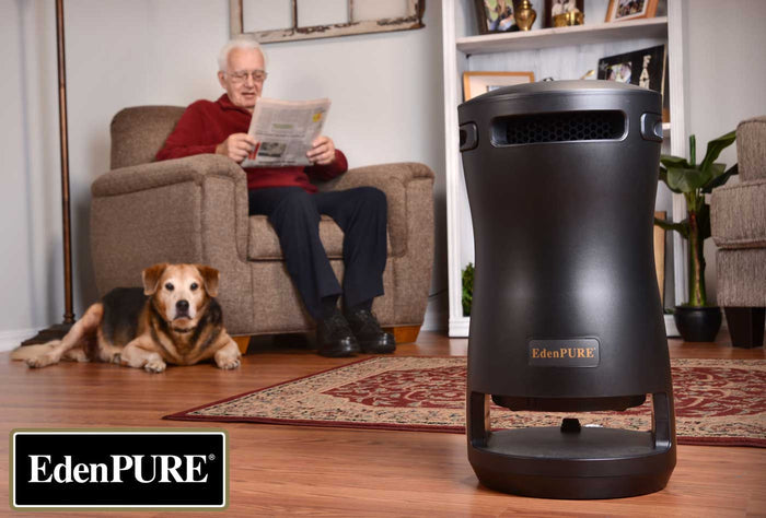 EdenPURE 360 Super Climater space heater and cooler in black on hardwood floor with elderly man reading and dog resting nearby