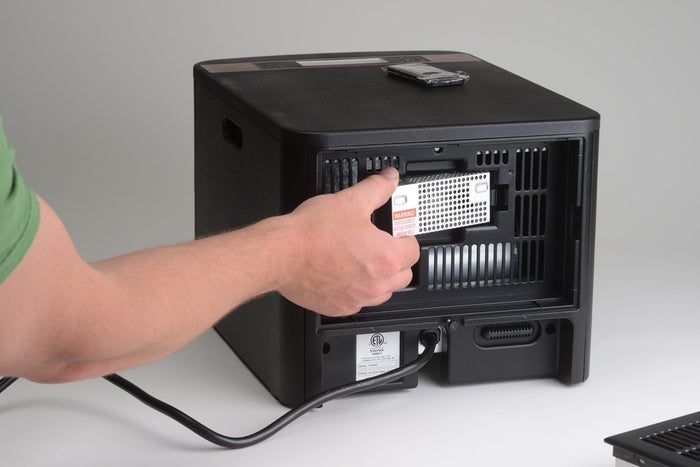 Hand installing HEPA filter into EdenPURE GEN21 Heater Air Purification Kit black casing unit