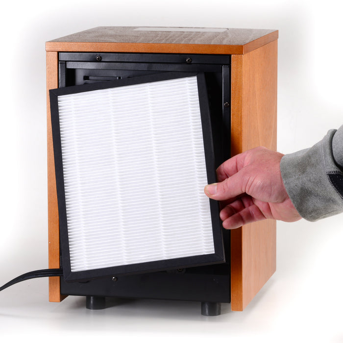 Hand placing replacement filter with black frame into EdenPURE GEN30 Elite Infrared Heater unit with wooden casing