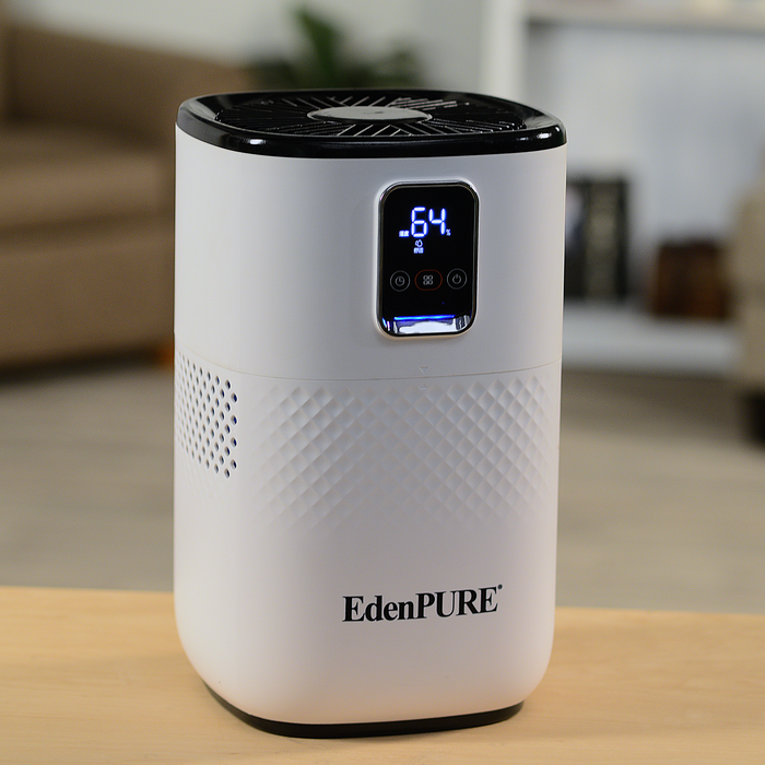 EdenPURE Mist-Free Humidifier in white with digital display showing humidity level on wooden surface in living room background