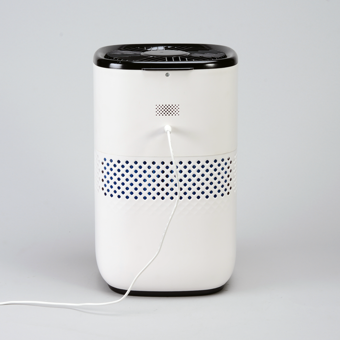 EdenPURE Mist-Free Humidifier in white and black with ventilation holes and power cord plugged in on gray background