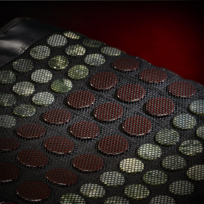 Close-up of EdenPURE TotalRELIEF Heating Pad with mesh covering dark and light circular ceramic stones on red background