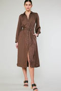 Woman wearing a brown button down satin dress with a belt on a white background