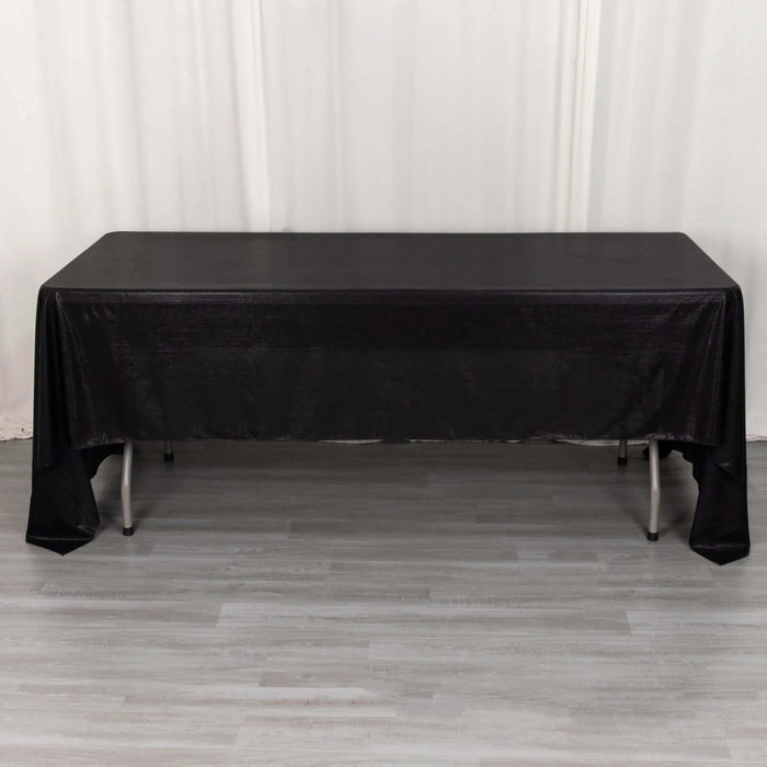Black tablecloth draped over a table on a light wooden floor.