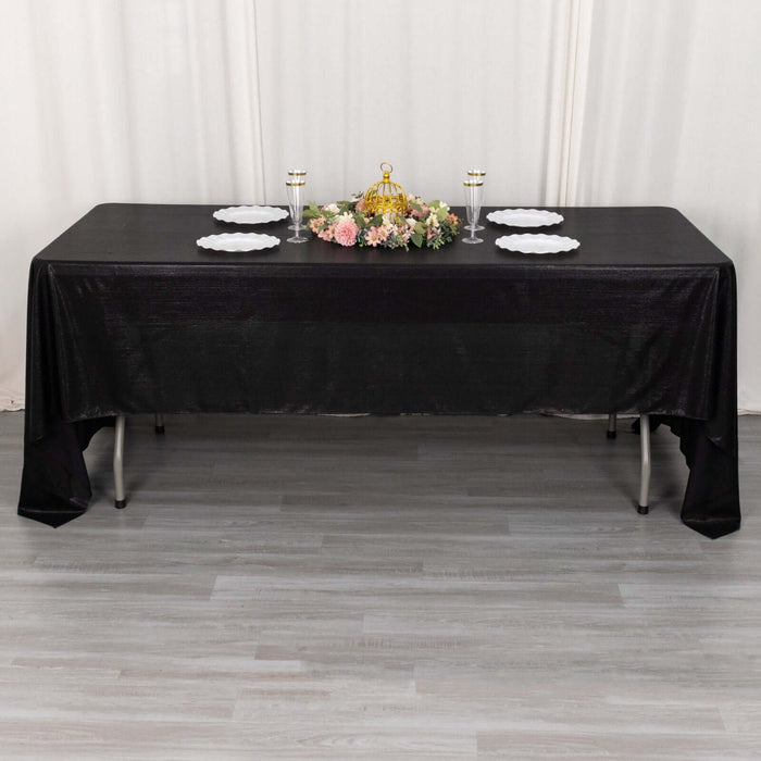 Black tablecloth draped over a table set with plates and a floral centerpiece.