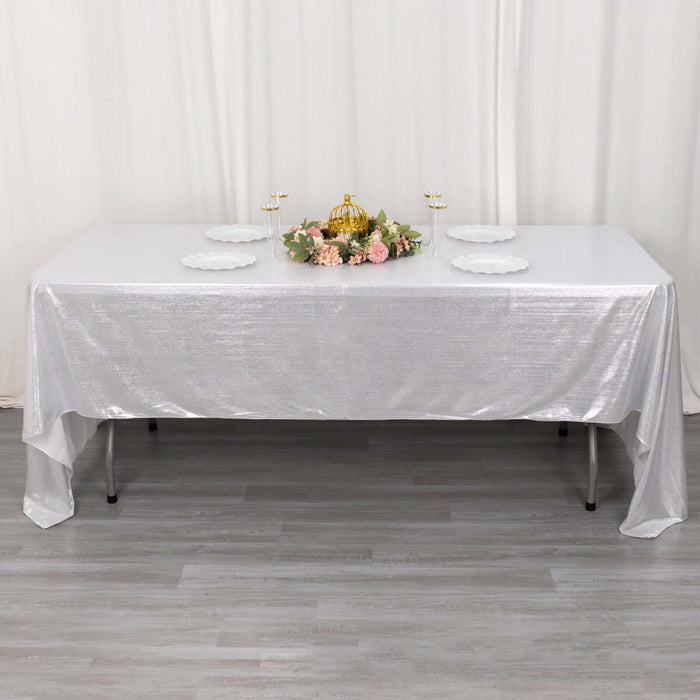 Elegant white table with silver tablecloth and floral centerpiece.