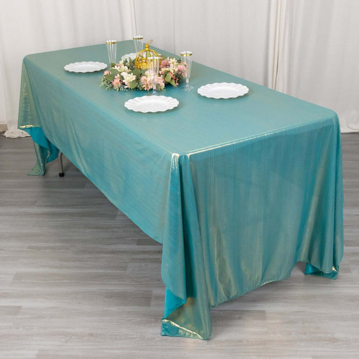 Teal tablecloth draped over a table, styled with plates and floral centerpiece.