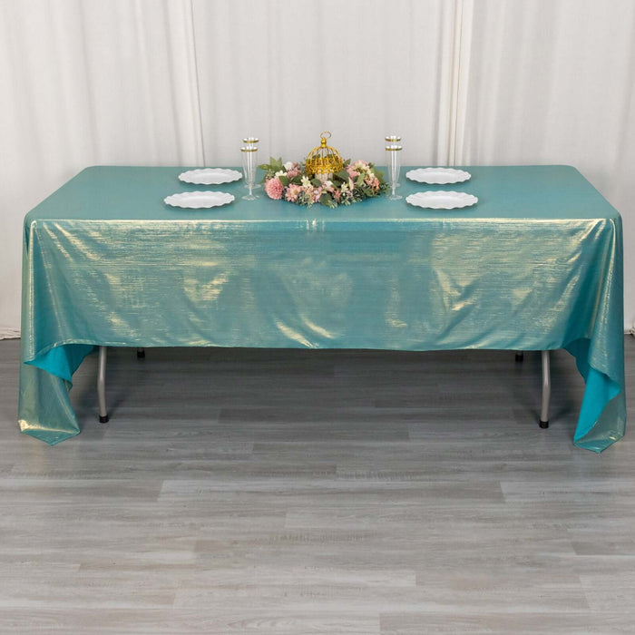 Teal tablecloth draped over a table with decorative centerpiece and plates.