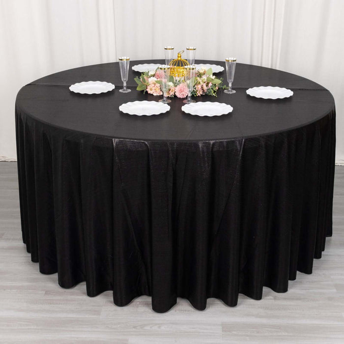Round black tablecloth with decorative plates and floral centerpiece.
