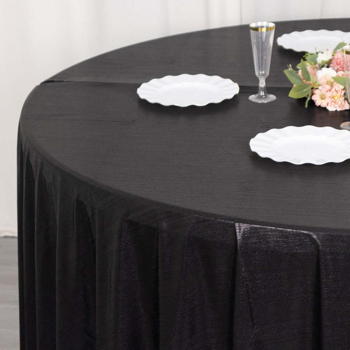 Black round tablecloth set on a table with white plates and floral decoration.