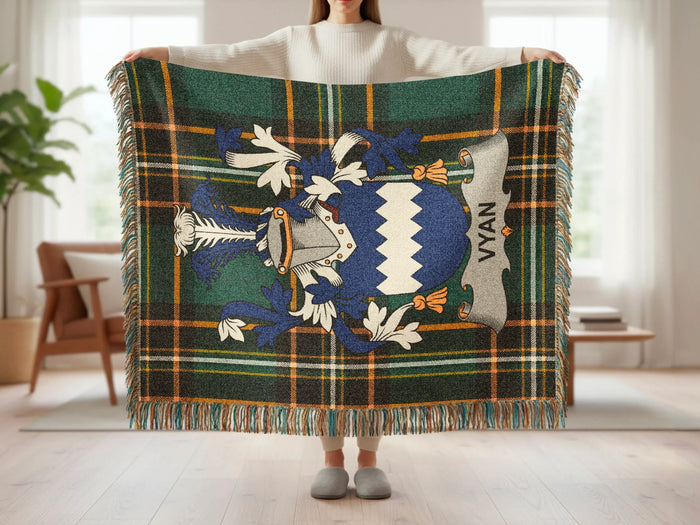 Tartan blanket with blue, white, and green plaid pattern and a coat of arms.